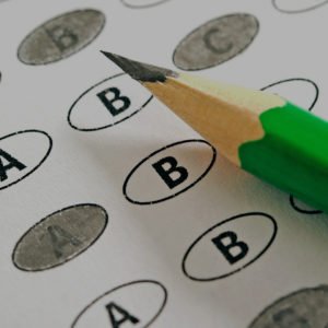 Close-up of a pencil resting atop a standardized test scoring sheet, commonly used for the act and sat, with answers a, b, c, or d filled in.