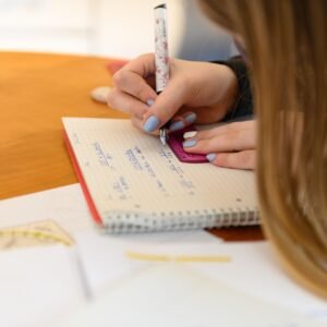 Close-up of a student using a ruler and notebook for geometry problem solving at a desk.