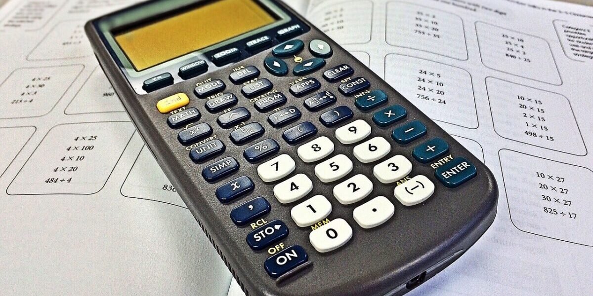 A scientific calculator resting on a math workbook with multiplication problems for 7th grade math help.