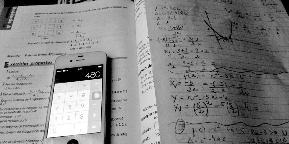 A phone calculator on top of a textbook and math tutoring notes.