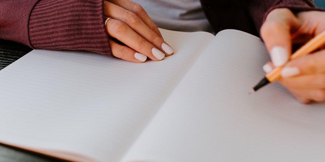 A person holding a pen over a blank notebook, ready to start memory exercises for studying.