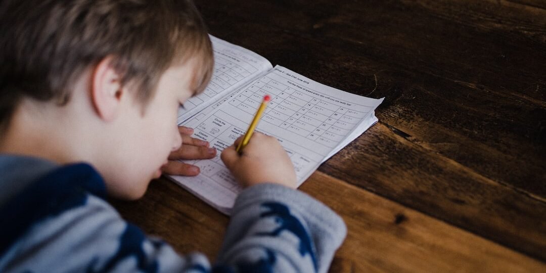 A kid working on homework during the summer.
